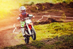 Fotolia 189702926 Subscription Monthly M 300x200 - Racer child on motorcycle participates in motocross cross-country in flight, jumps and takes off on springboard against sky. Concept active extreme rest teenager.